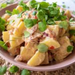 thermomix potato salad in pink bowl with cress on top, on woven placemat