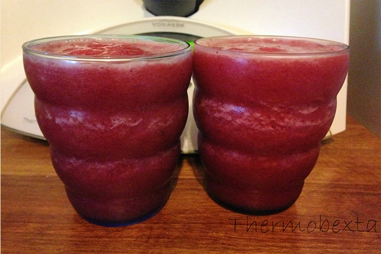 cherry banana mocktails, two glasses of pink slushie drink on wooden board in front of thermomix