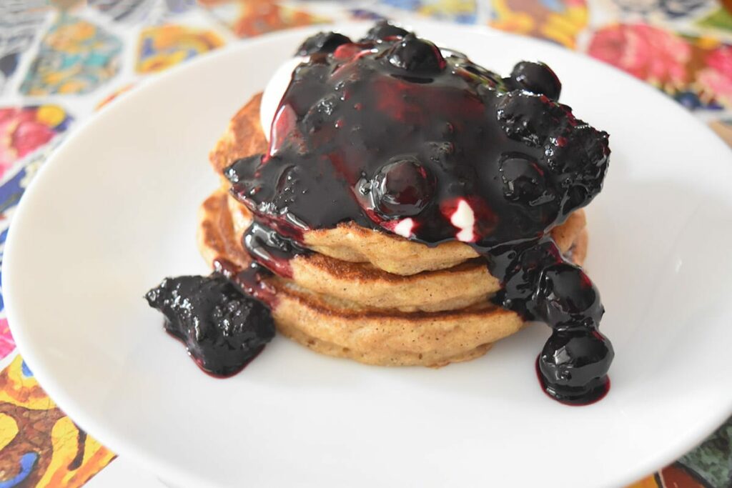 thermomix blueberry sauce drizzled over pancake stack on white plate