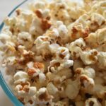 sweet and salty popcorn in glass bowl on white surface